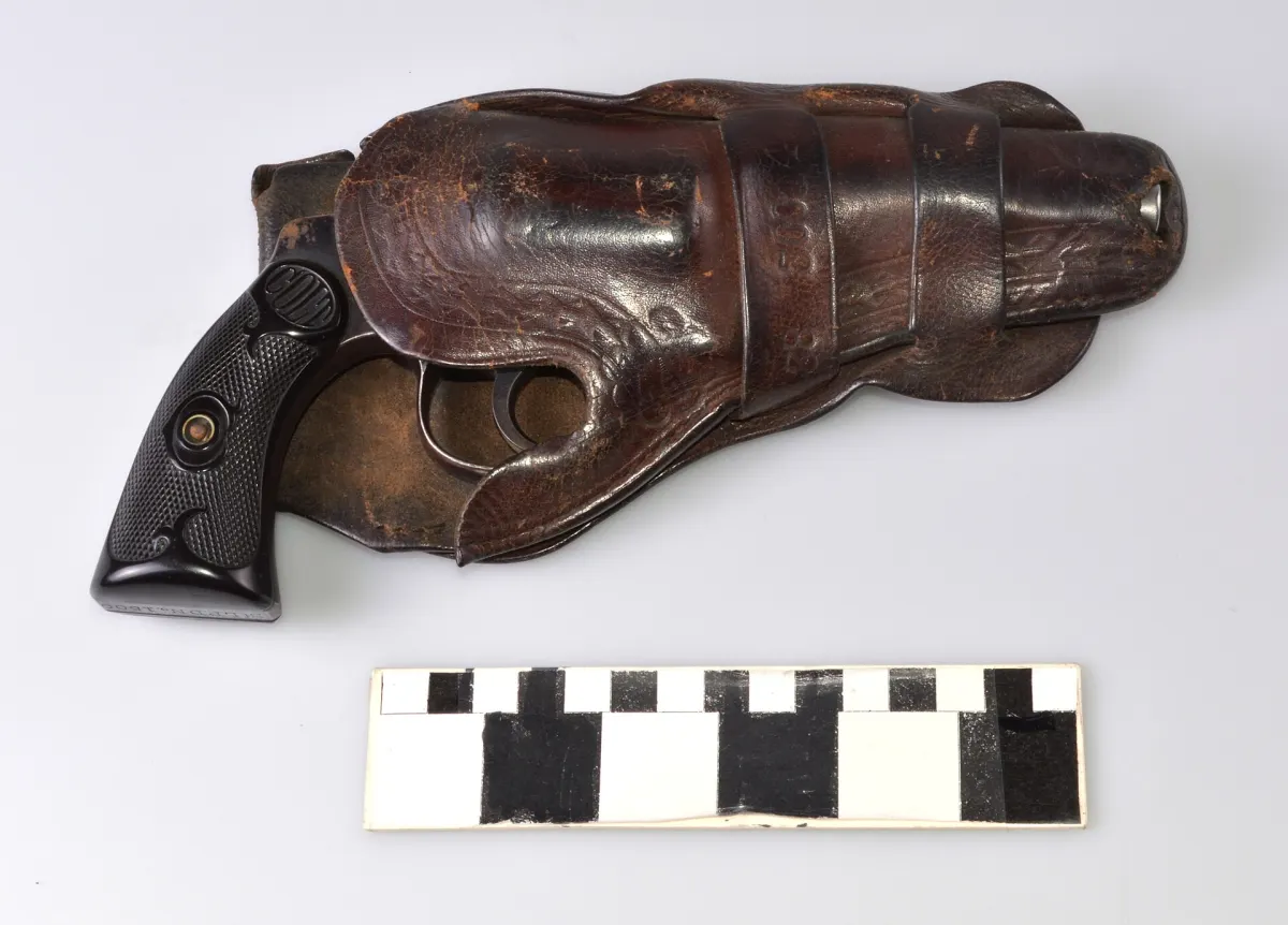 A police service revolver in a worn leather holster, photographed for a museum collection