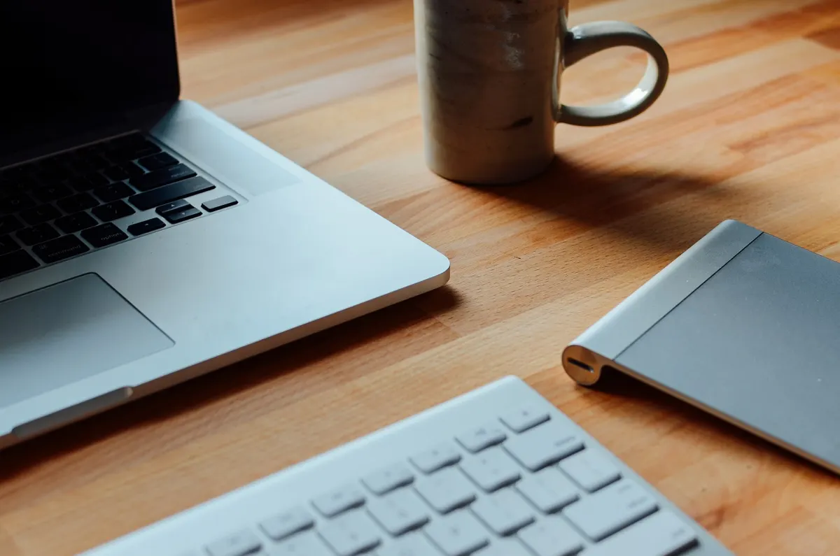 A laptop and a coffee mug on a wooden desk