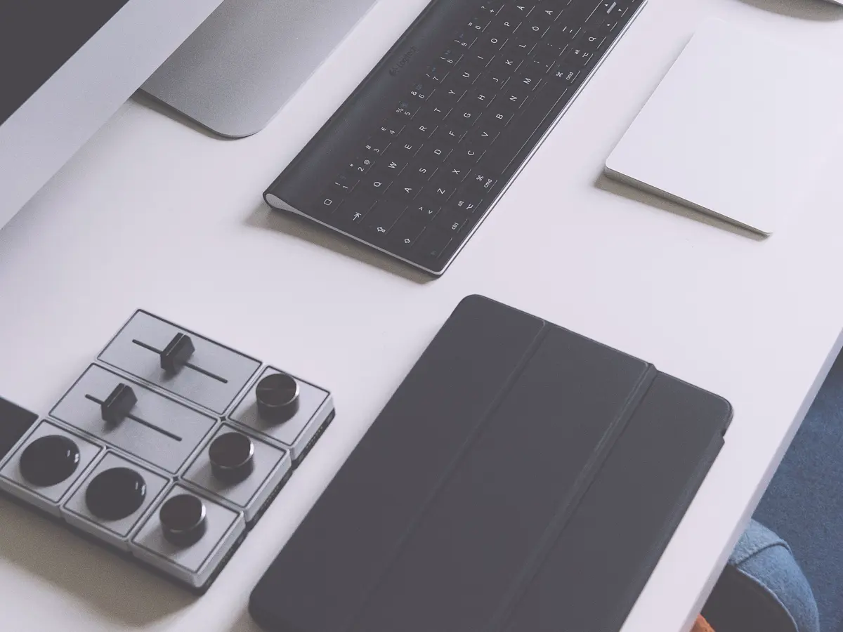 A keyboard, tablet and controls laid out on a white desk