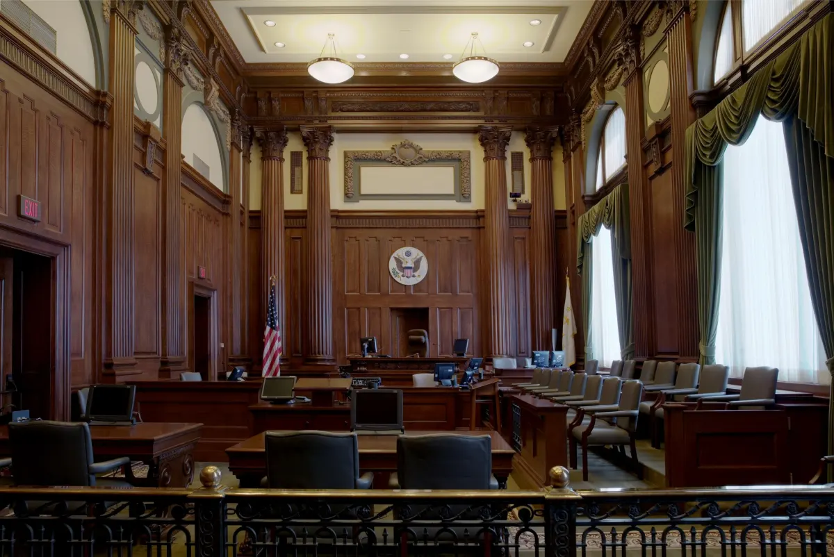 An empty federal courtroom with wood paneling and a judge's bench