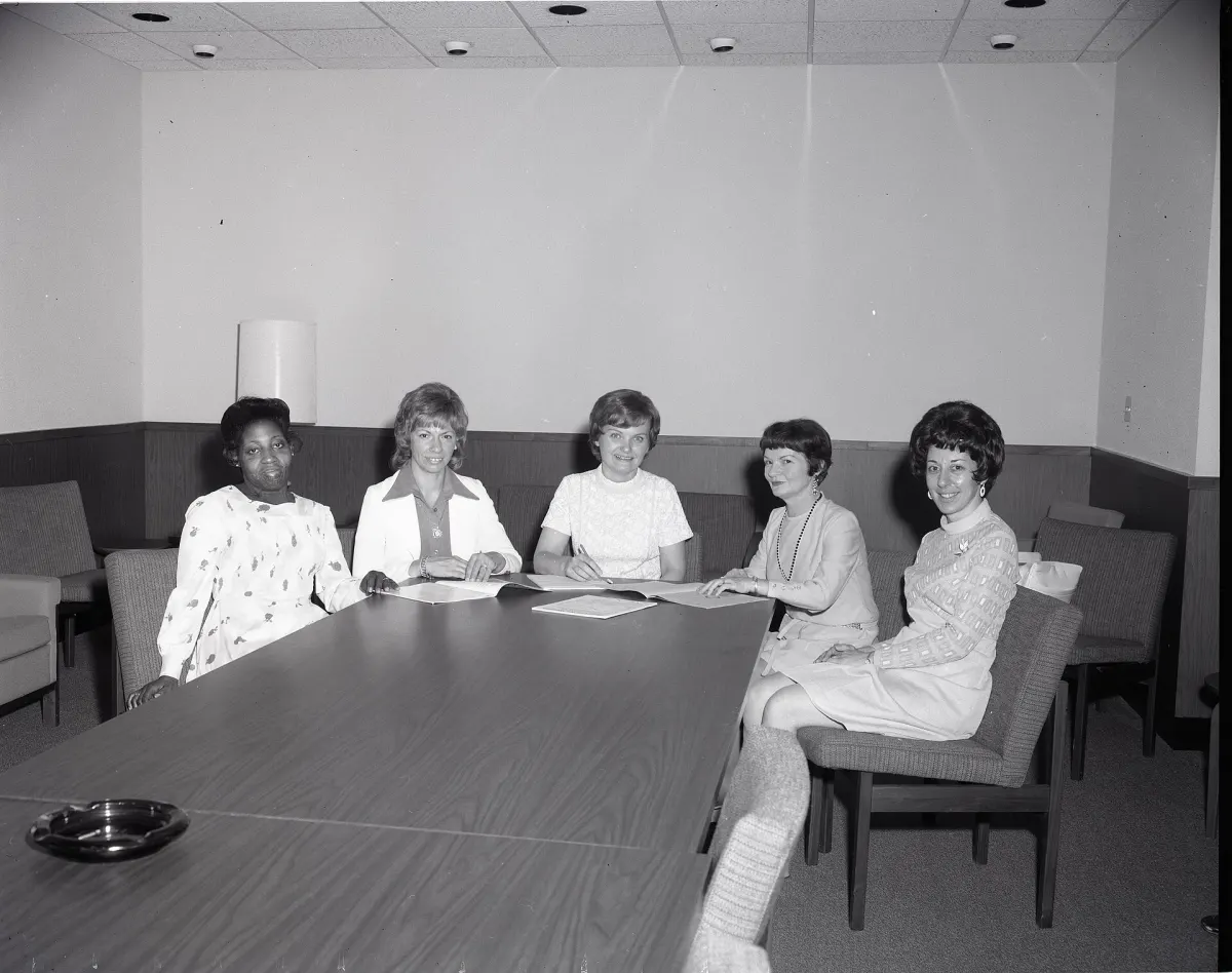 Five women seated at a conference table in a 1974 photo